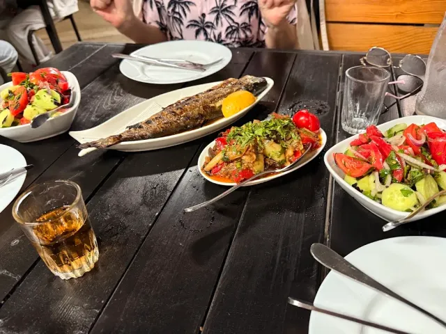 דג שלם צלוי עם פלח לימון על שולחן כהה, לצד קערות סלט ירקות