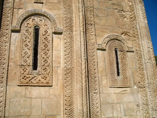 שני חלונות צרים בקיר אבן ממוסגרים בגילופים גיאומטריים עשירים