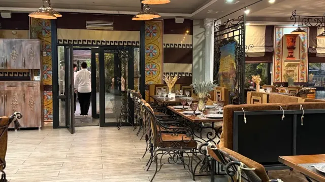 אולם מסעדה עם עמודים מעוטרים, כיסאות ברזל מחושל ושולחנות ערוכים