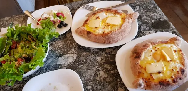 שתי סירות בצק ממולאות גבינה עם חלמון וחמאה, לצדן קערת סלט ירוק
