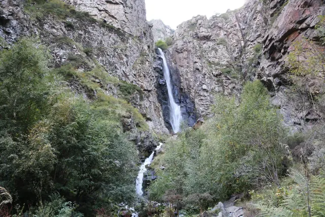 מפל דק ניתך במורד מצוק גבוה בתוך ערוץ מיוער